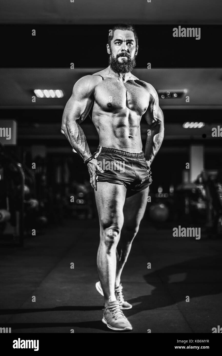 Atleta culturista musculoso hombre posando en el gimnasio. Foto de stock