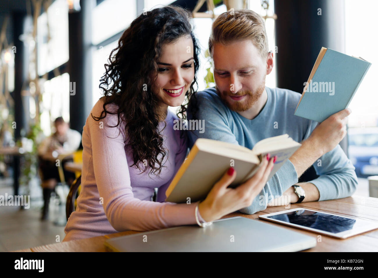 Los jóvenes estudiantes dedicar tiempo a la lectura de libros en la cafetería. Foto de stock