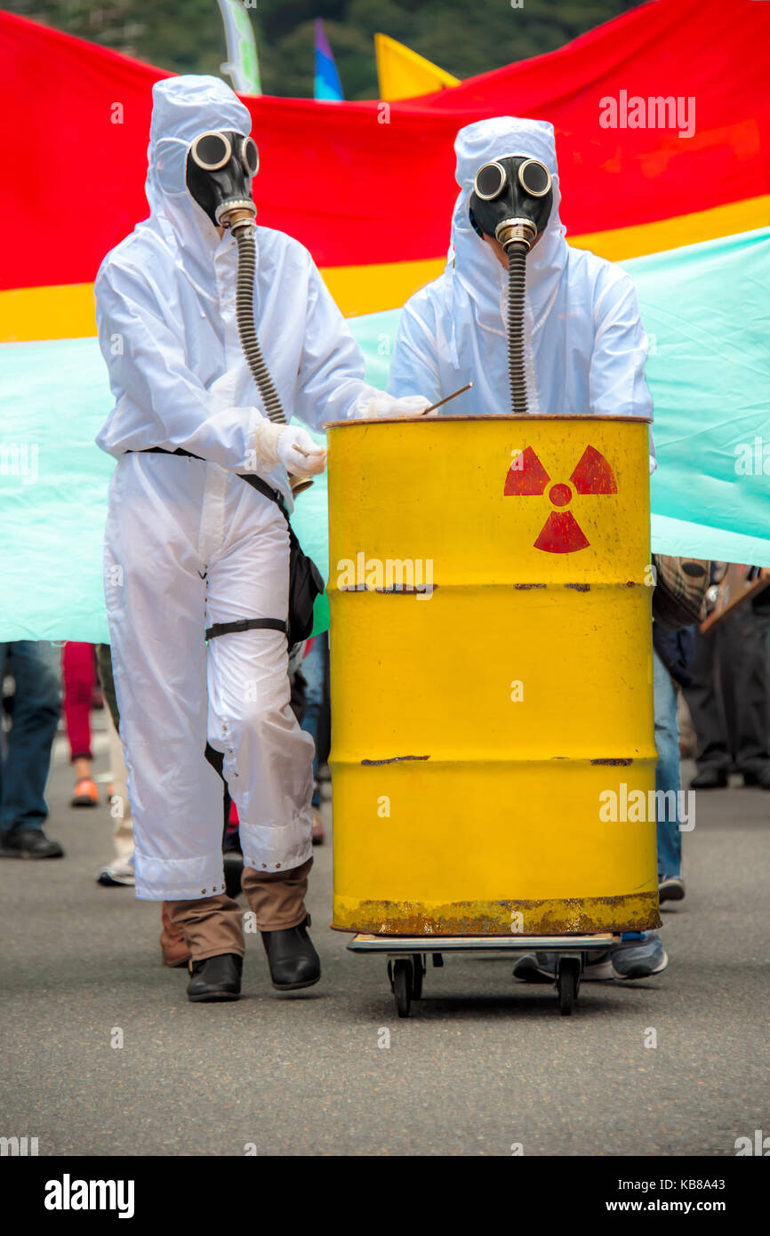 dos-hombres-en-bio-hazard-trajes-y-mascaras-de-gas-dos-hombres-en-biohazard-trajes-y-mascaras-de-gas-de-pie-detras-de-un-oxidado-tanque-con-proyecto-el-simbolo-nuclear-kb8a43.jpg