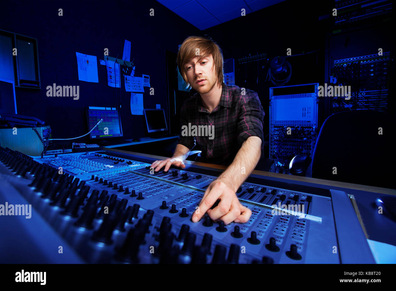 Hombre utilizando una mesa de mezclas de sonido en un estudio de grabación Foto de stock