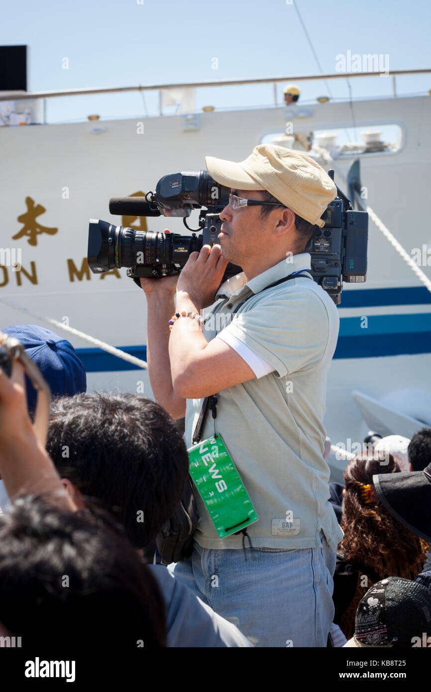 Nagasaki, Japón- abril 28, 2012: un reportero con una cámara de televisión portátil sobre su hombro en Nagasaki tall ships festival. Foto de stock