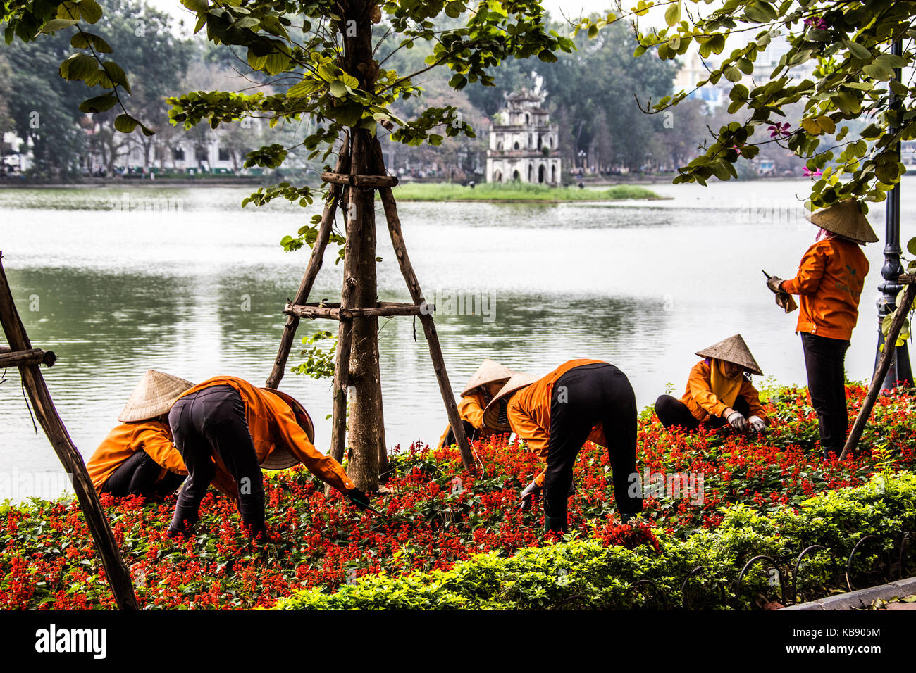 La mujer tendiendo flores en frente de Thap Rua templo o torre de la tortuga, el lago Hoan Kiem, Hanoi, Vietnam Foto de stock