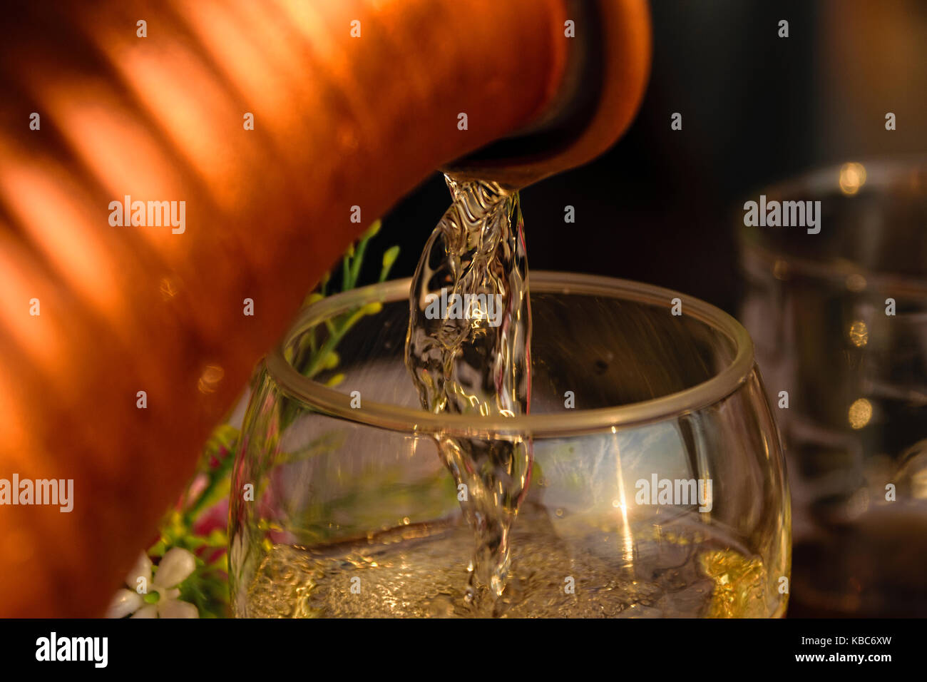 Close-up de vino blanco que se vierte en copas de vino durante el atardecer Foto de stock