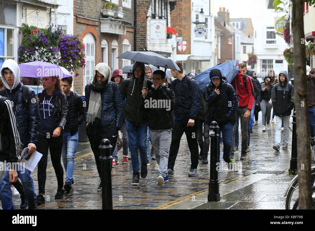 Canterbury, Kent, UK. 29 de septiembre de 2017. Un grupo de jóvenes visitando Canterbury sobre un paño húmedo día caminando en la lluvia con el paraguas. Crédito de la foto Pablo Lawrenson /Alamy Live News Foto de stock