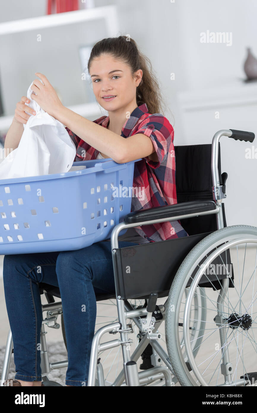 Mujer joven doblar ropa desde su silla de ruedas Fotografía de stock - Alamy