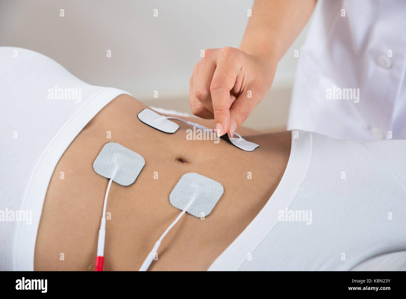 Close-up de terapeuta de colocar los electrodos en el estómago de la mujer  Fotografía de stock - Alamy