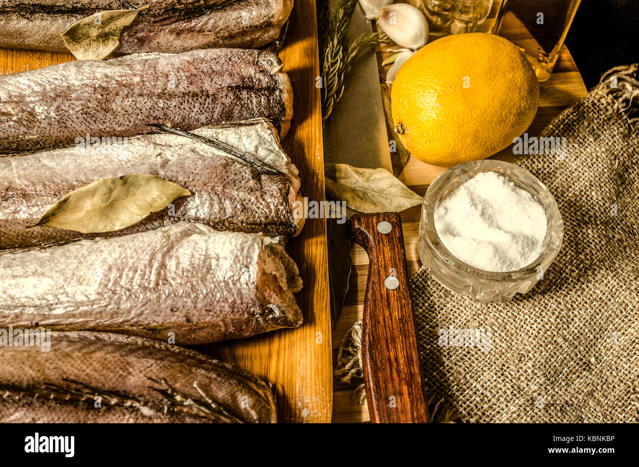 La merluza congelada con especias y cocina cuchilla para picar madera rayas Foto de stock