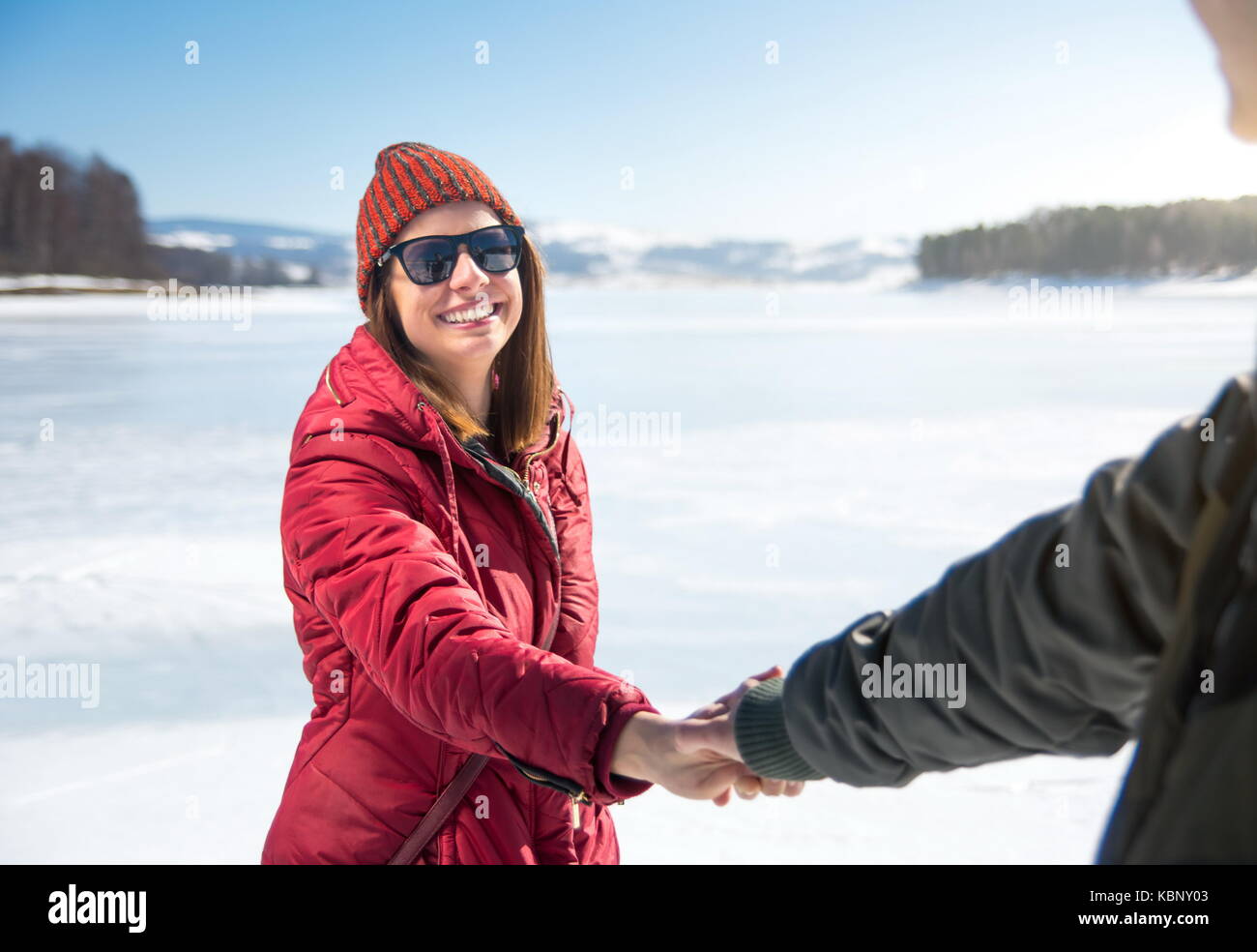 Par la celebración de manos sobre un lago congelado en un soleado día de invierno Foto de stock