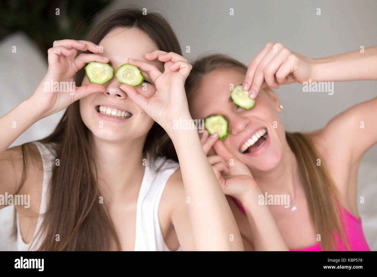 Dos amigas ser tonto poniendo pepinos en los ojos. Foto de stock