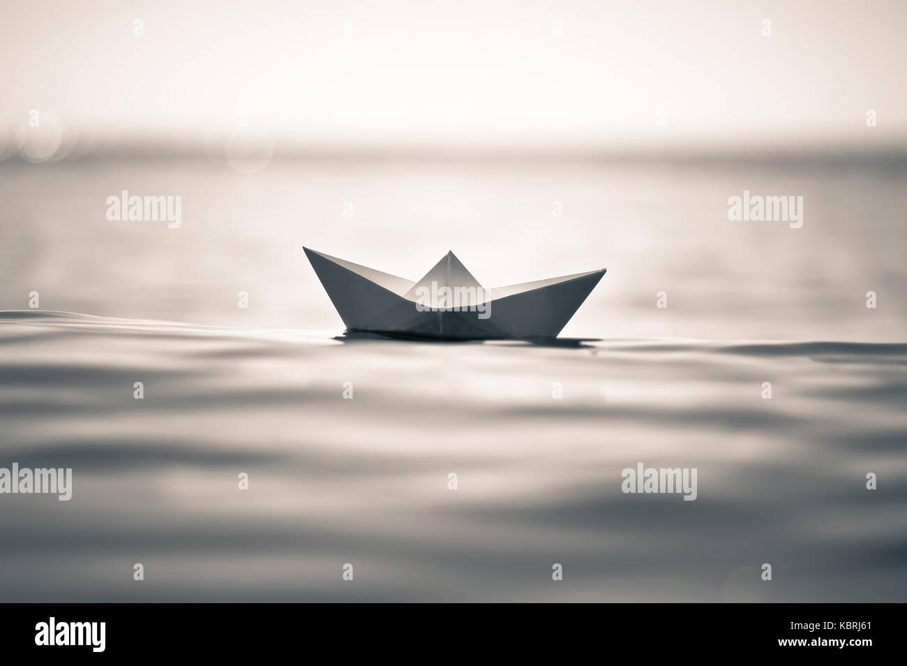 Barco de papel sobre el mar ola tonos sepia Foto de stock