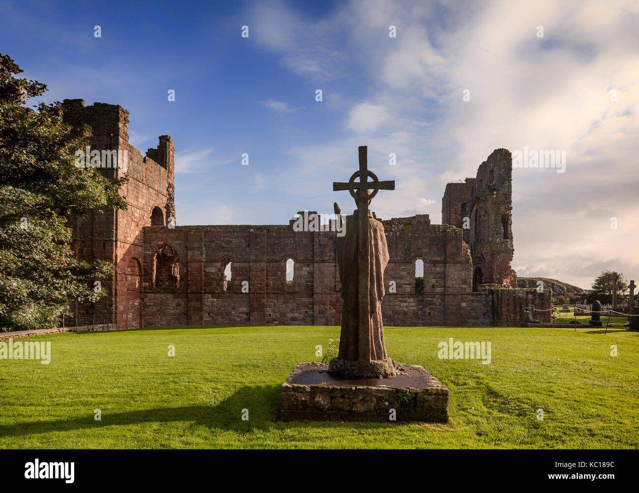 La estatua de St Cuthbert junto a las ruinas de la iglesia, construida alrededor de 1150, en el lugar donde su cuerpo fue enterrado. isla sagrada, Northumberland, Inglaterra Foto de stock