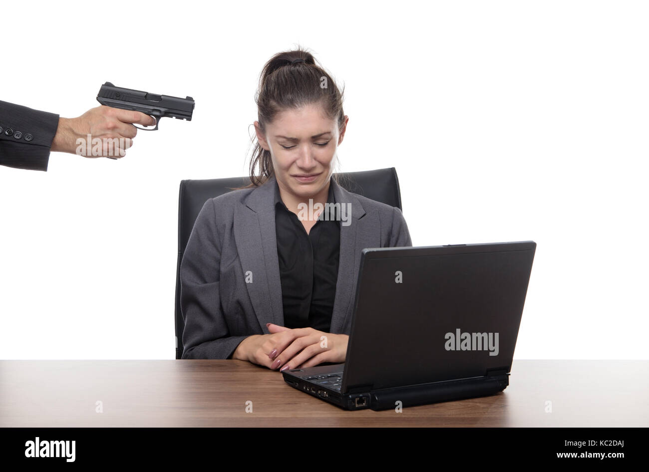 mujer-de-negocios-sentada-en-su-escritorio-con-una-pistola-apuntando-a-su-cabeza-kc2daj.jpg