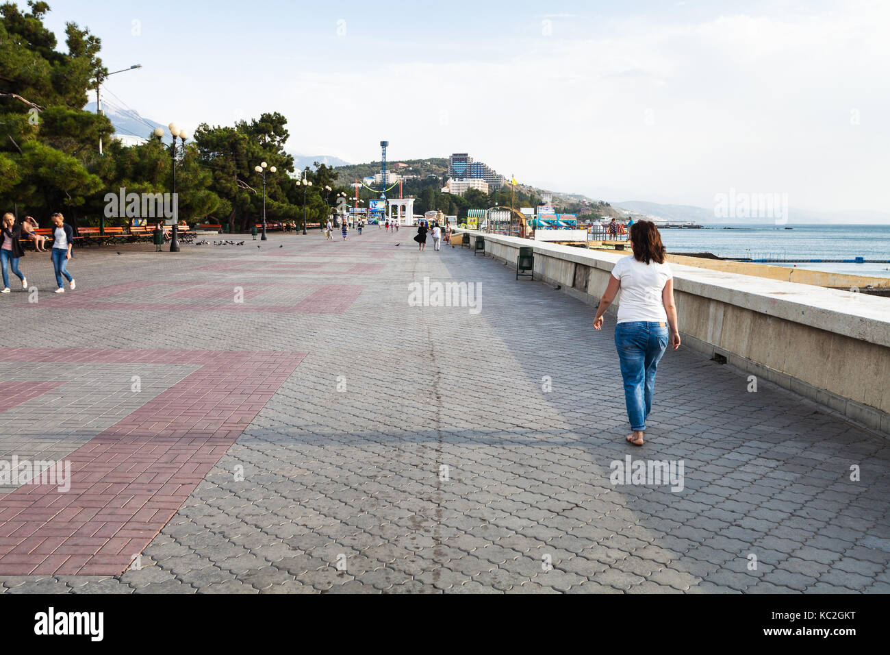 Alushta, Crimea - , 22 de septiembre de 2017: Hay turistas que caminan por la calle lenin terraplén en alushta Ciudad en crepúsculo matutino. Alushta es el balneario en Foto de stock