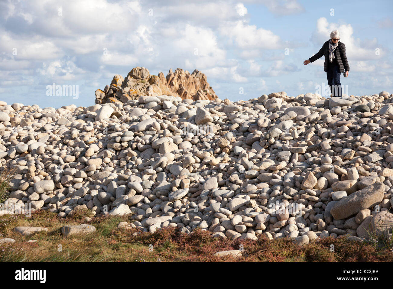 En la costa Noroeste de la Isla de Brehat (Bretaña - Francia),un anciano turista que busca una perfecta piedra como recuerdo. Foto de stock