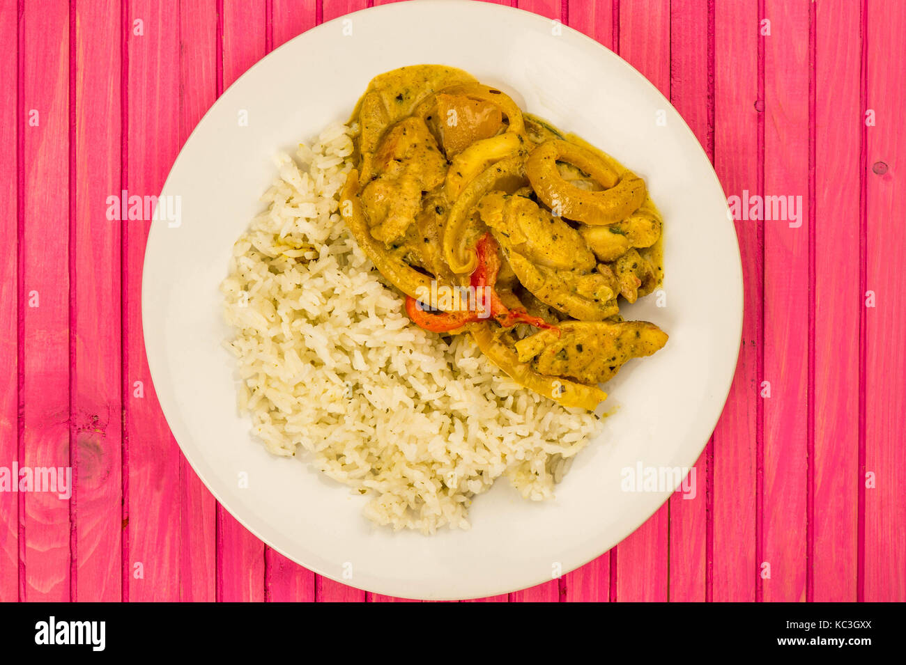 Estilo tailandés curry panang de pollo con arroz jazmín contra un fondo de madera rosa Foto de stock