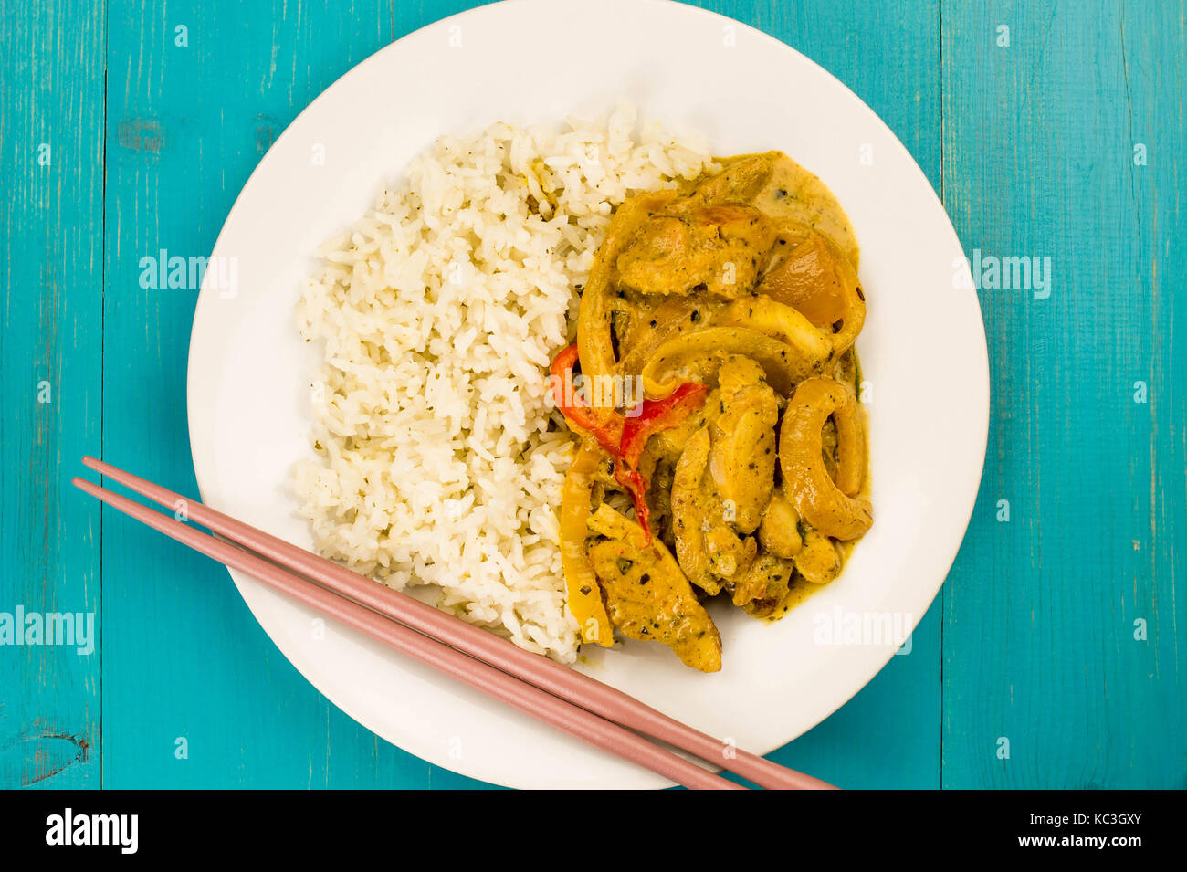Estilo tailandés curry panang de pollo con arroz jazmín azul contra un fondo de madera Foto de stock