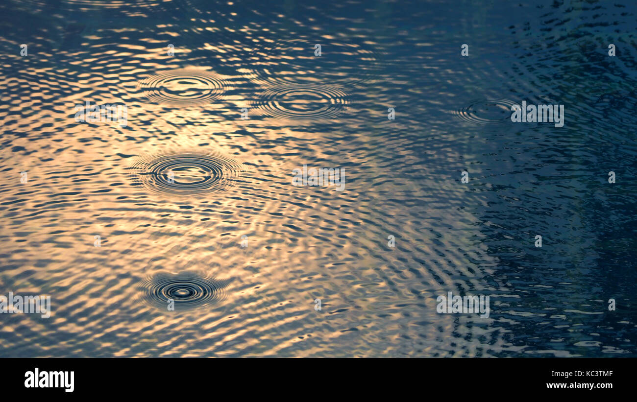 Gota de lluvia sobre la superficie de la piscina de agua y tienen un efecto de ondulación de textura. Foto de stock