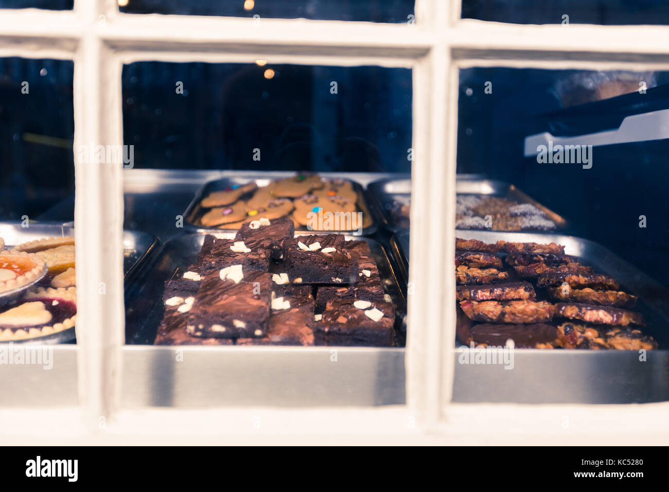 Productos horneados, bizcochos y galletas, visto a través de un escaparate de panadería con el frío tono de color, ideal para las vacaciones de fondo del tema Foto de stock