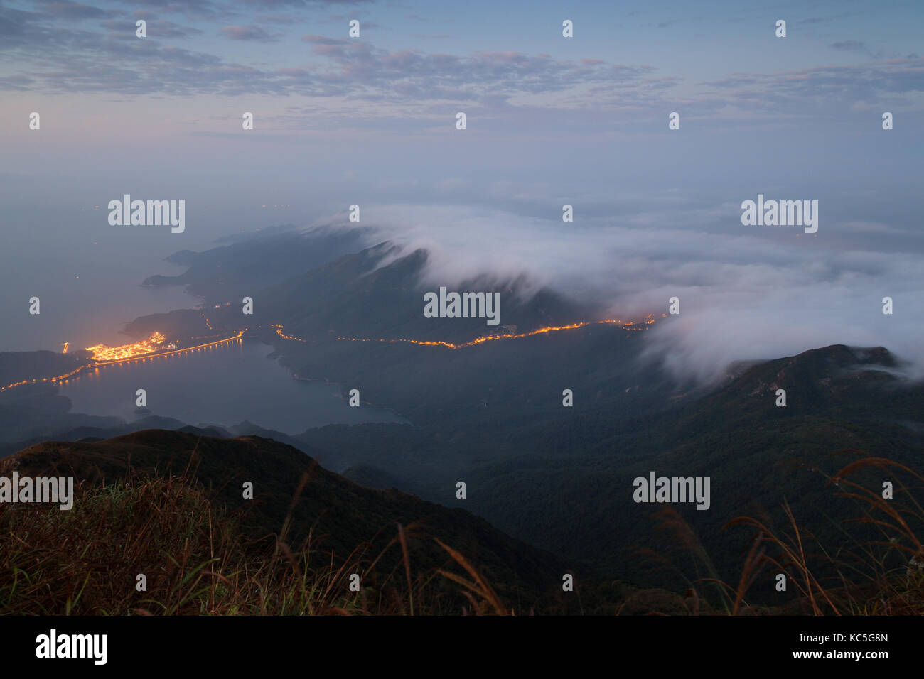 Nubes sobre las colinas en la isla de Lantau, visto desde el pico lantau (el segundo pico más alto de Hong Kong, China) al amanecer. Foto de stock