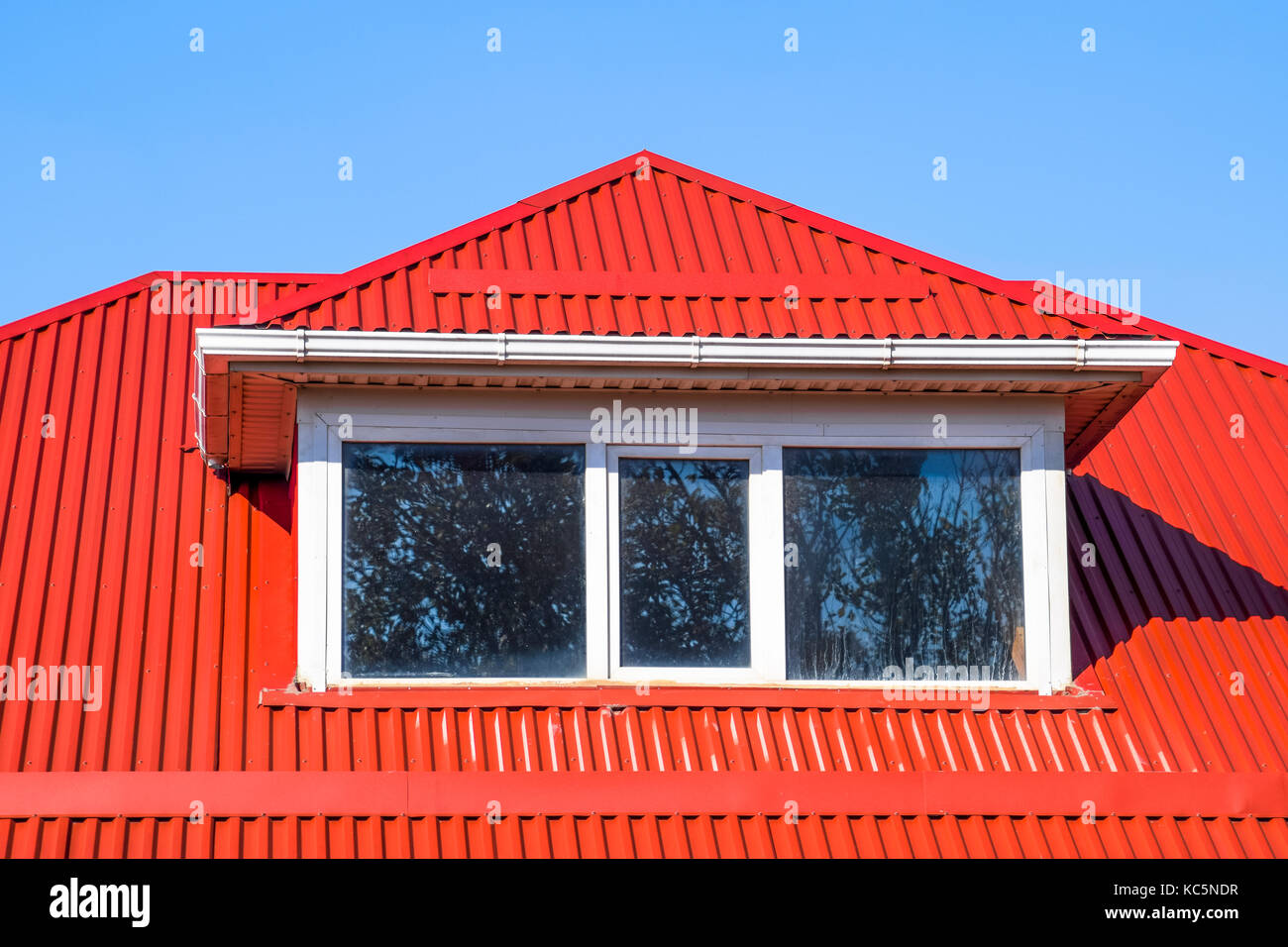 Apariencia por ciento entusiasta Casa con ventanas de plástico rojo y un techo de chapa corrugada. Techos de  perfil metálico forma ondulada en la casa con ventanas de plástico  Fotografía de stock - Alamy