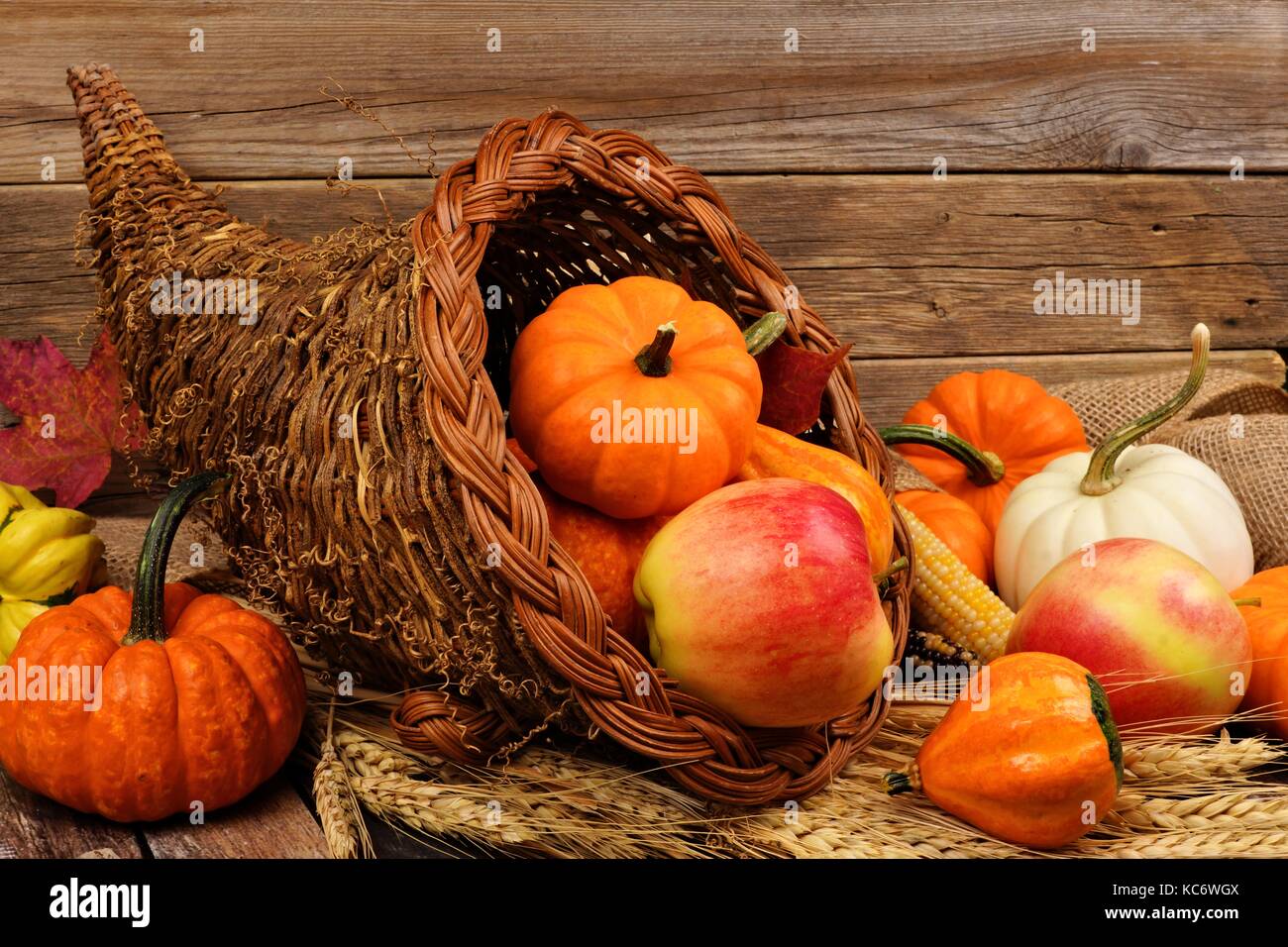 Thanksgiving cornucopia llena de calabazas y frutas contra un fondo de madera rústica Foto de stock