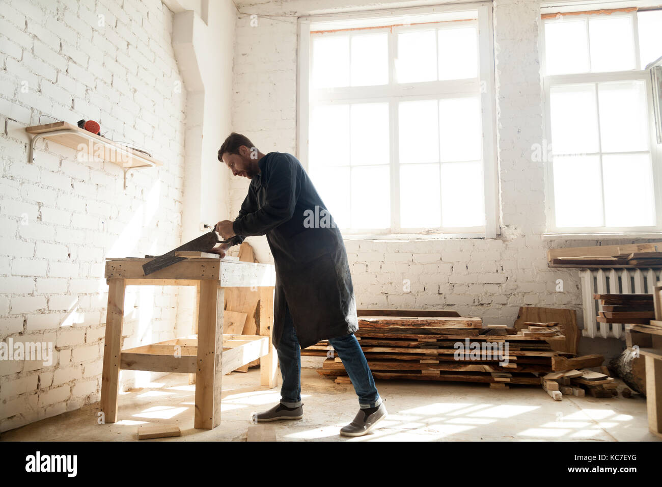 Carpintería y construcción. Carpenter usando serrucho para el aserrado de wo Foto de stock