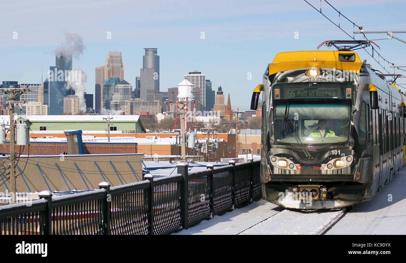 Minneapolis, Minnesota/Estados Unidos - 15 de enero de 2011: un tren lightrail mcto se aproxima a una estación con la silueta de la ciudad de Minneapolis, en el fondo. Foto de stock