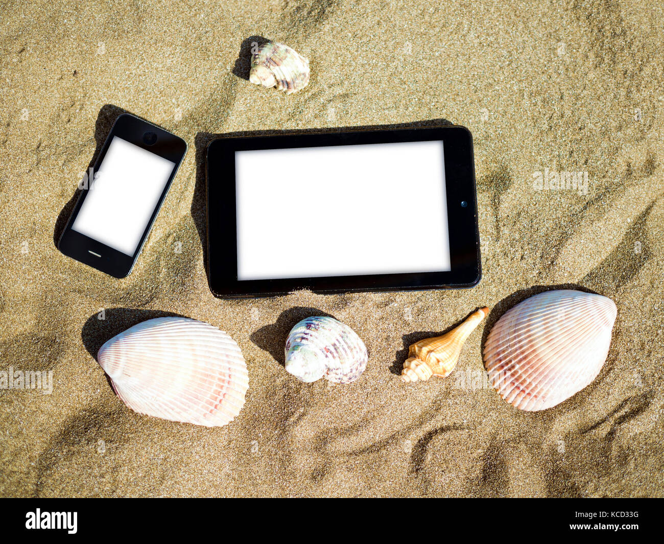 Dos teléfonos inteligentes con conchas en la playa de verano Foto de stock