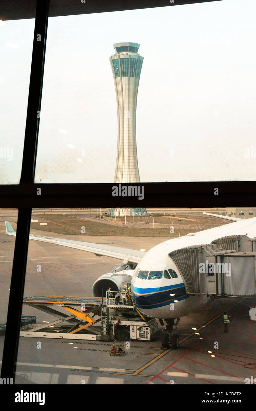 El aeropuerto internacional de changshui Kunming, Yunnan, China. La torre de control y el avión de pasajeros en el delantal preparando para el vuelo visto desde la explanada de la ventana Foto de stock