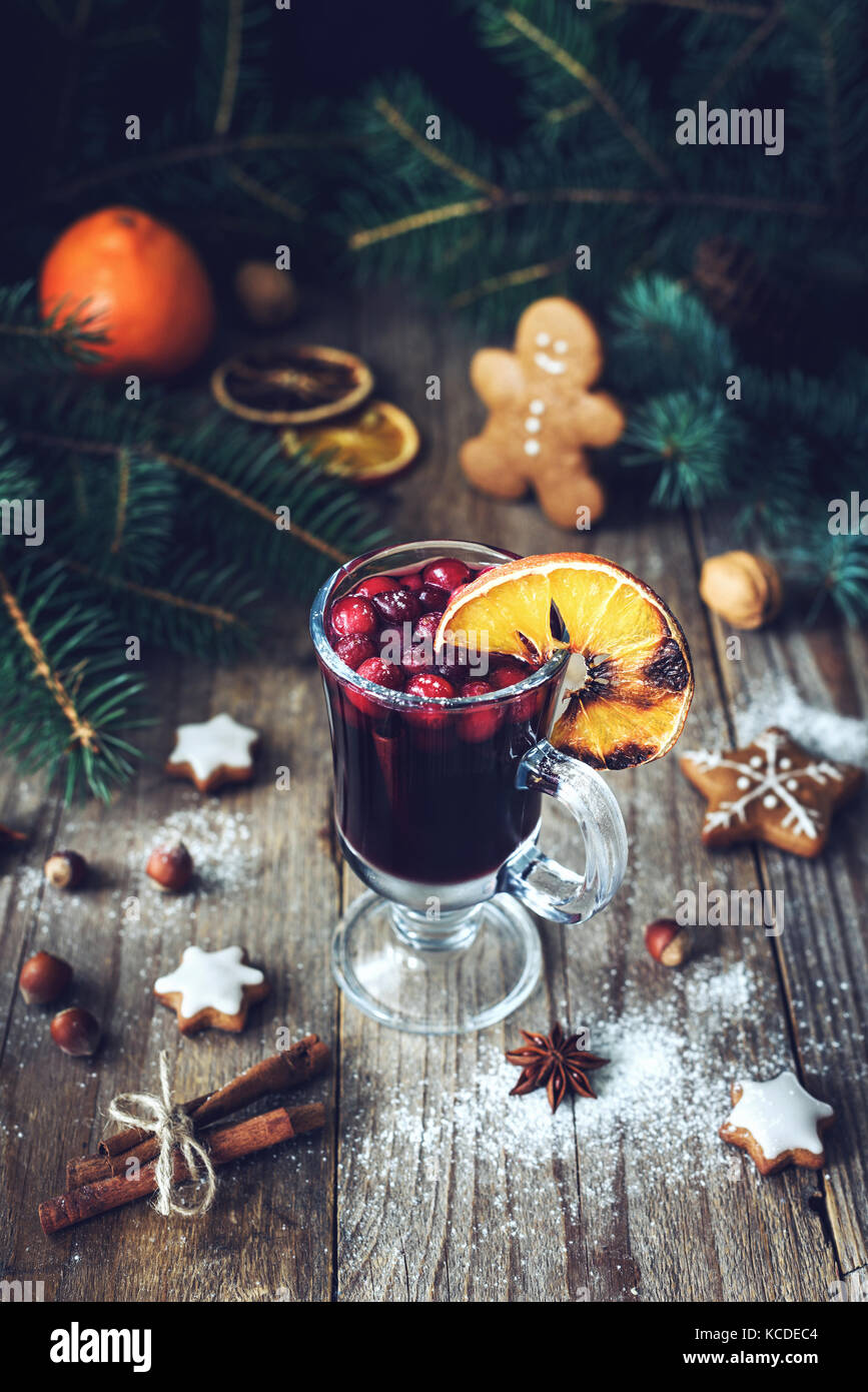 Vino caliente en cristal con arándanos rojos y especias decorado con naranja quemado. Navidad vacaciones en concepto de comida bebida. Foto de stock
