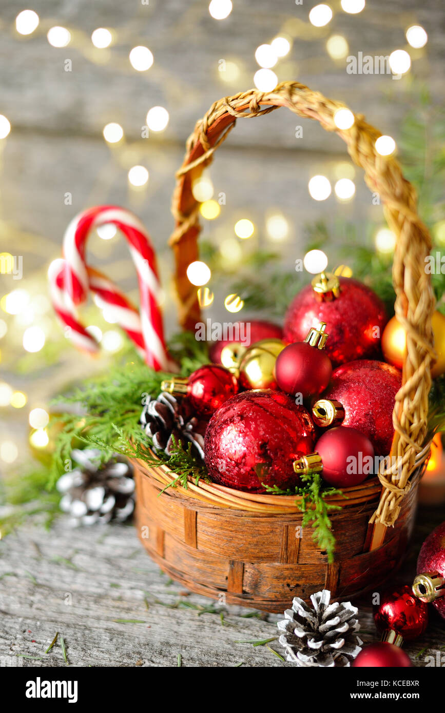 Cesta de Navidad con Vintage regalos y luces brillantes. Bolas rojas,  piñas, lollipop sobre mesa de madera copia espacio dibujando la nieve  Fotografía de stock - Alamy