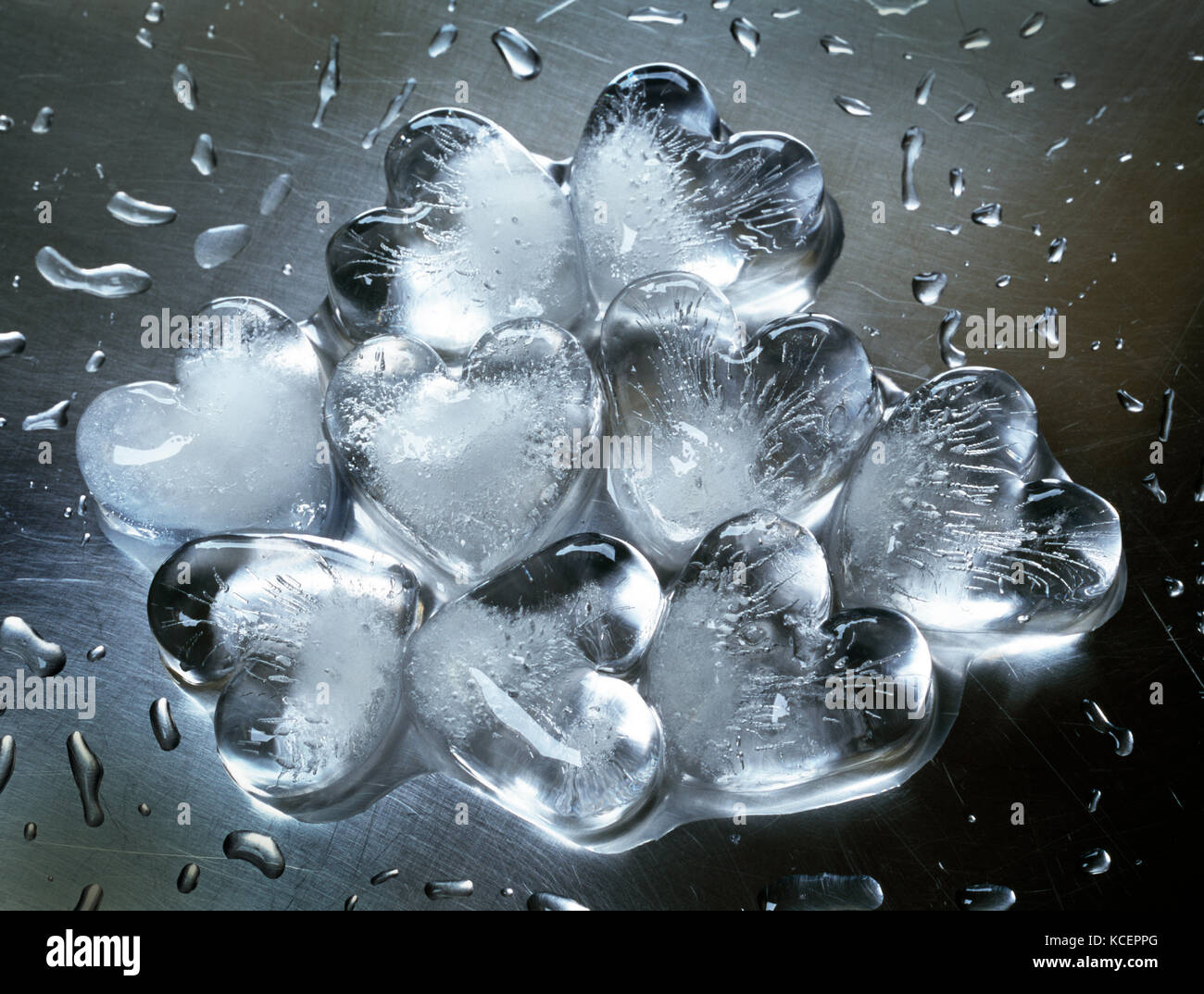 Grupo de nueve corazones cubitos de hielo en acero inoxidable rayado. Empezando a derretirse. Foto de stock