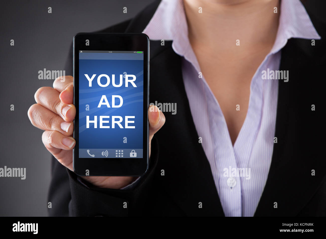 Close-up de persona que muestre su anuncio aquí texto en el teléfono móvil contra el fondo gris Foto de stock