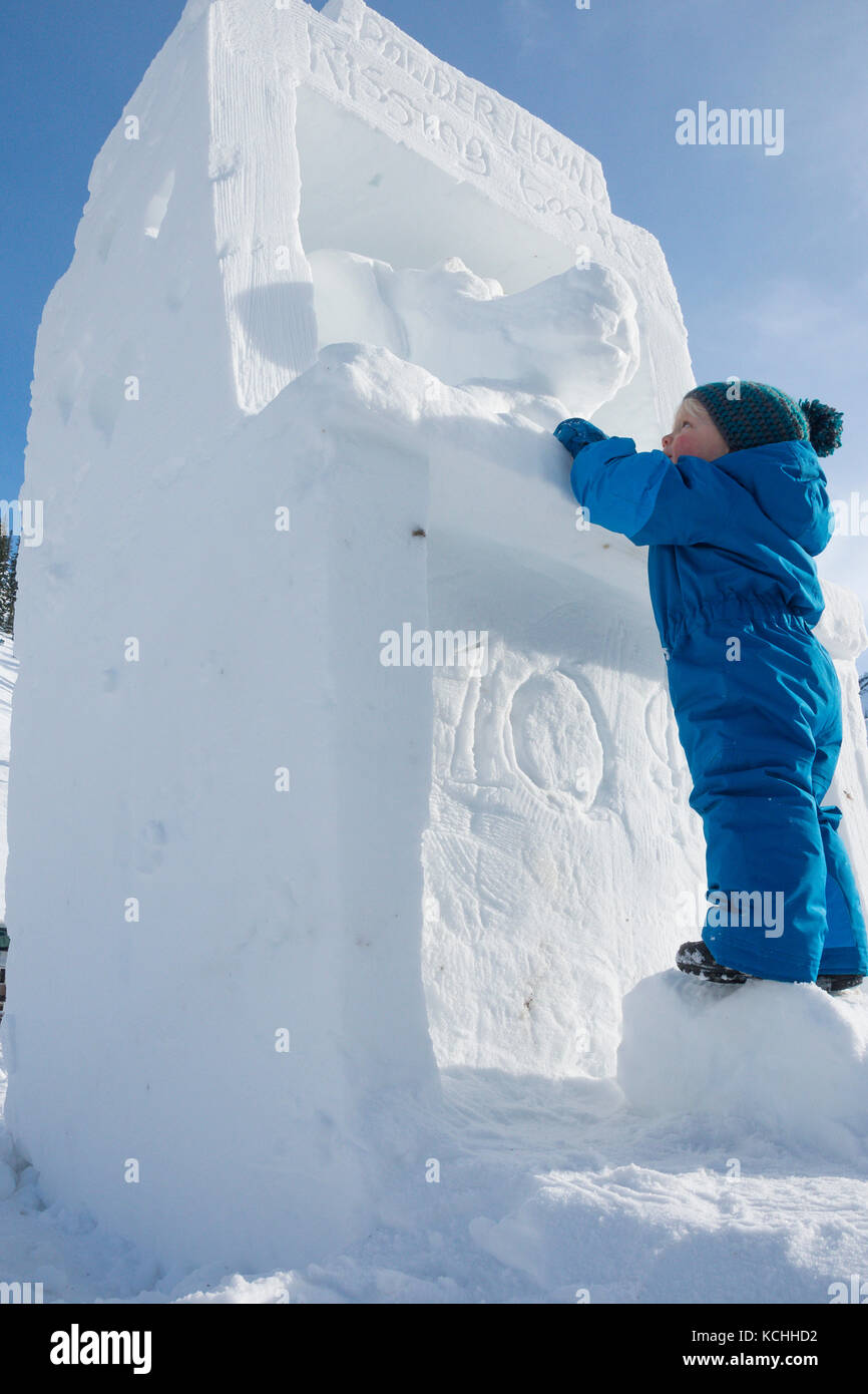 Un niño retira la nieve una escultura que representa un stand de besar por diez centavos Foto de stock