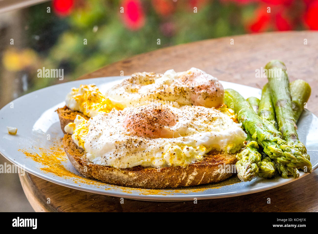 Huevo escalfado con cúrcuma sobre tostadas de pan de masa fermentada con espárragos Foto de stock