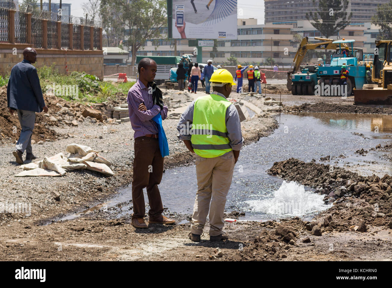 Los trabajadores de la construcción inspección de fugas en las tuberías de agua que se derrama en el área de la construcción, de Ngong Road, Nairobi, Kenia Foto de stock