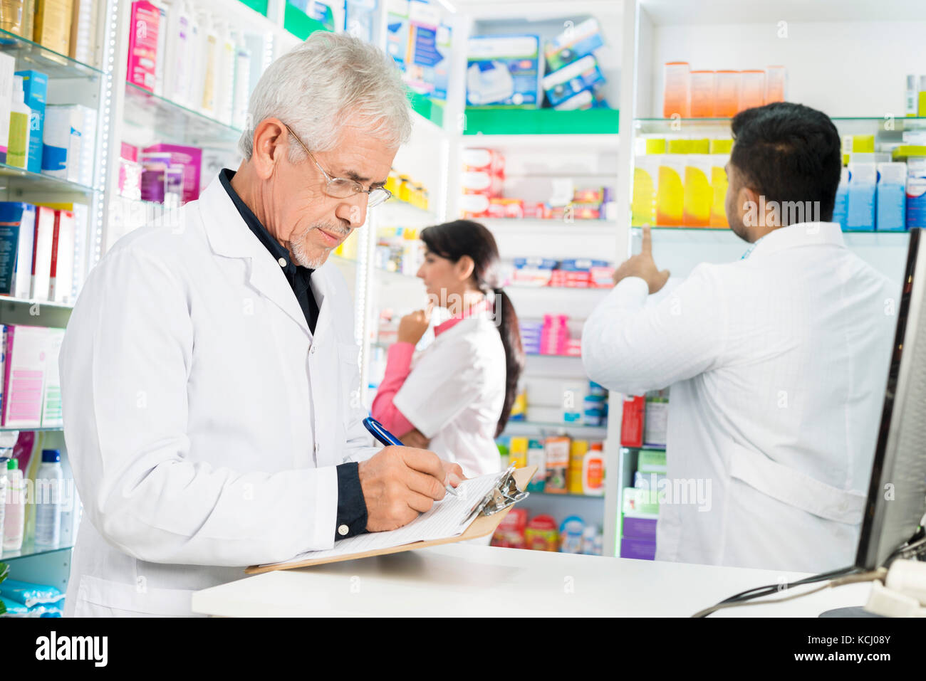 Farmacia escrito el portapapeles mientras sus compañeros trabajan en la farmacia Foto de stock