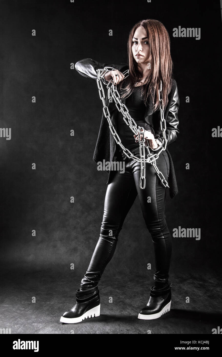 joven en una ropa negra con una cadena sobre oscuro Fotografía stock - Alamy