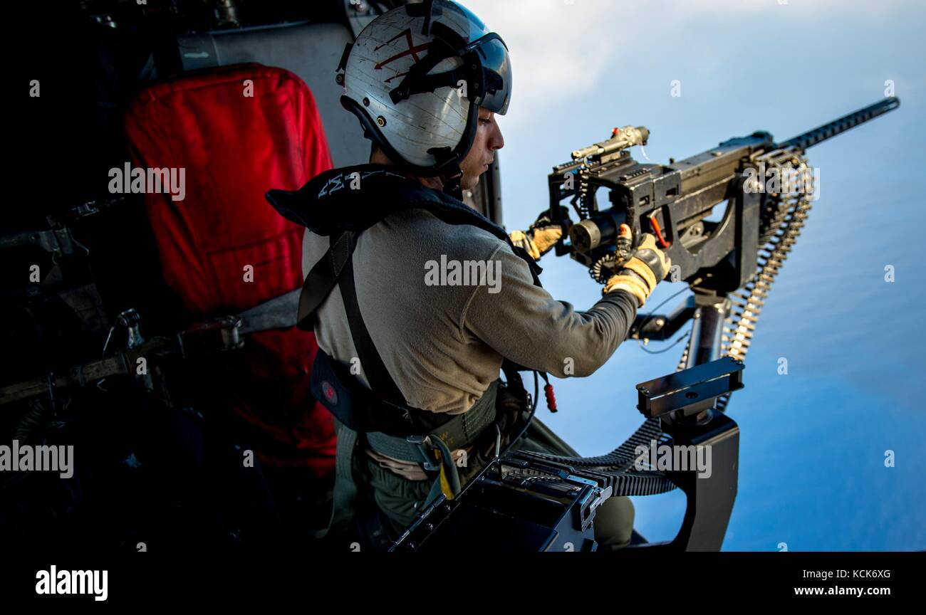 Un marinero estadounidense mans un gau-21 calibre .50 rápido-fuego de ametralladoras marina MH-60 Seahawk helicóptero en vuelo, 20 de julio de 2017 sobre el mar mediterráneo. (Foto por zachary wickline mcss via planetpix) Foto de stock