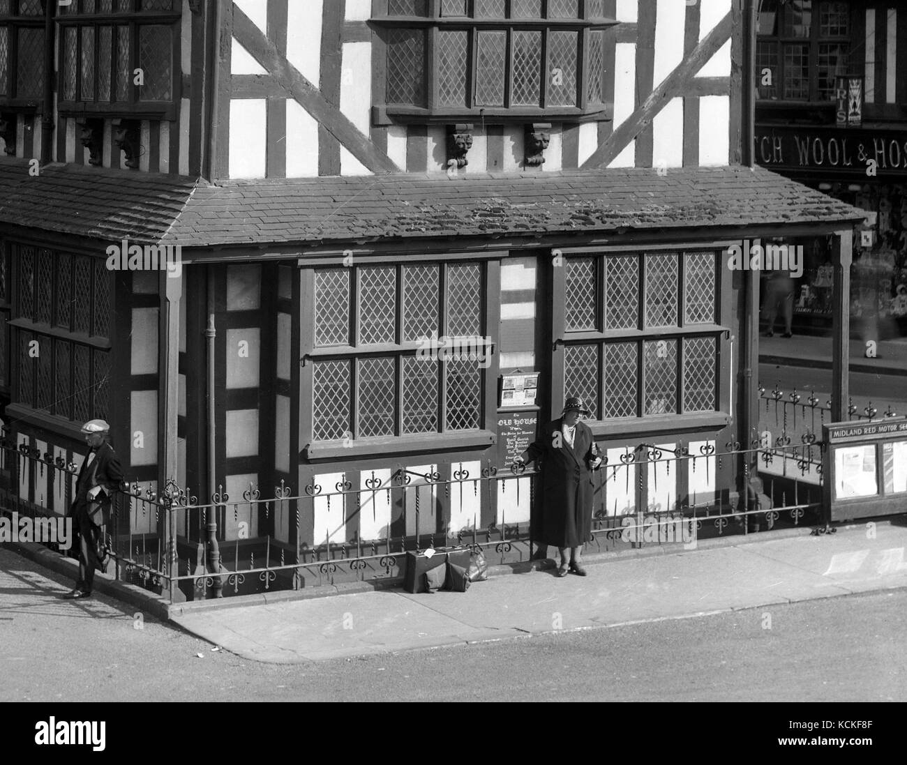 La antigua casa en Hereford en 1928 con la mujer esperando un autobús rojo Midland Motor Company. Foto de stock