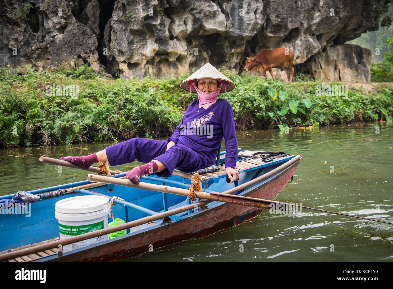 Una dama remo su barco con sus pies en Ninh Binh, Vietnam Foto de stock
