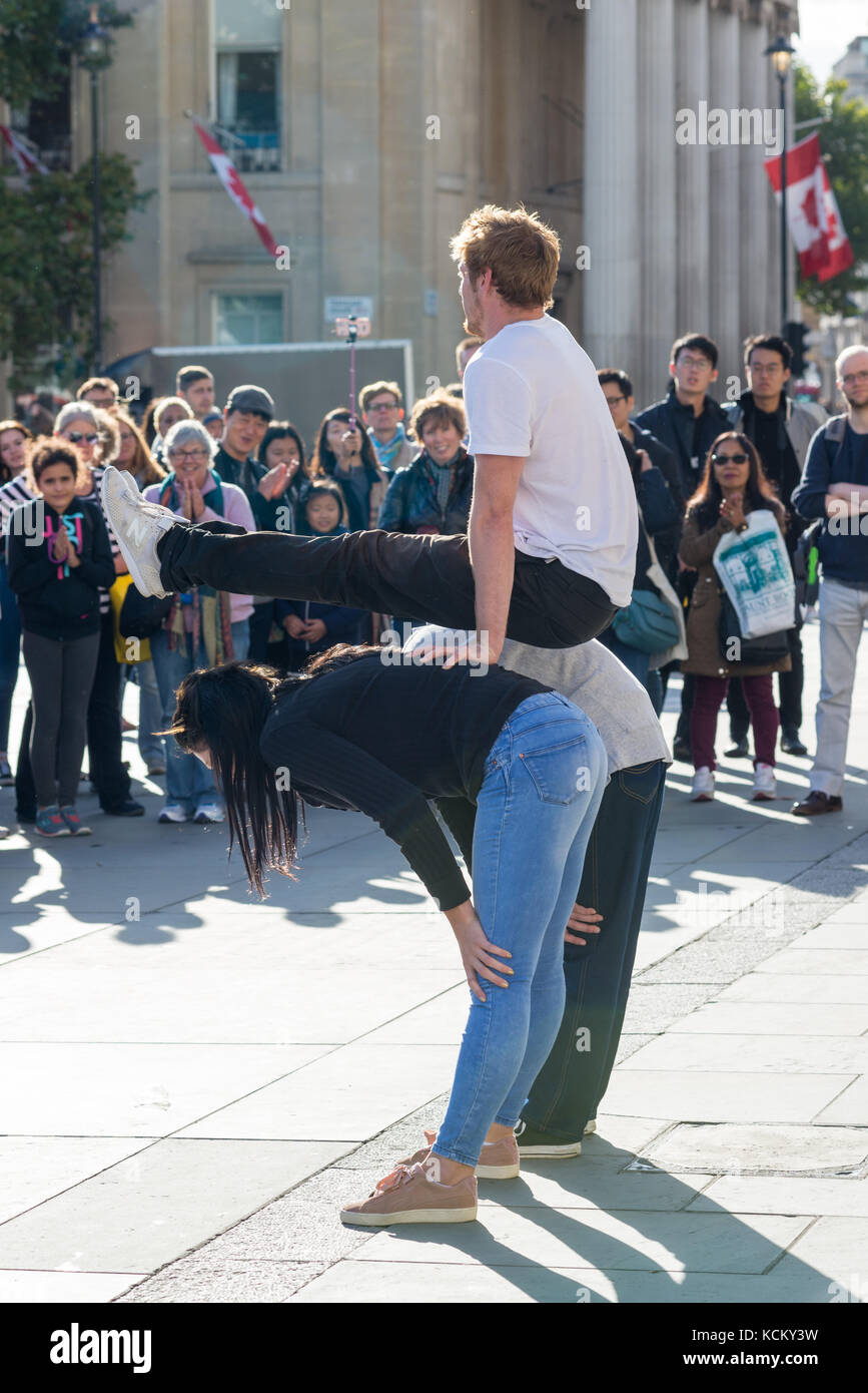 Ejecutante de la calle entretenido Multitudes en Trafalgar Square, Londres, Inglaterra, Reino Unido, con la participación de la audiencia, algunas piruetas acrobáticas. Foto de stock