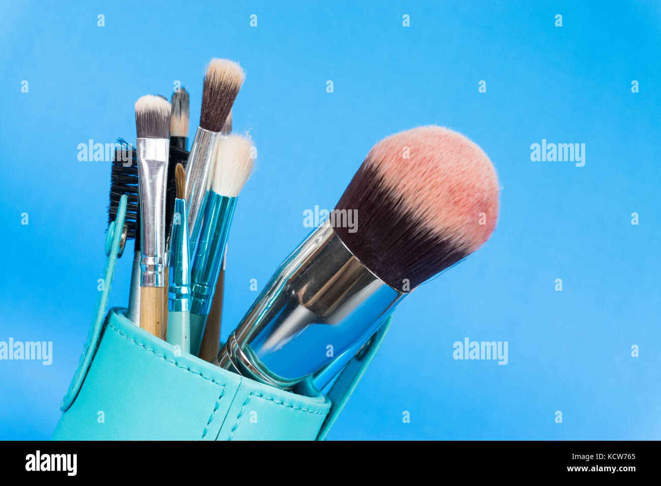 Un conjunto de pinceles de maquillaje en fondo azul. Foto de stock