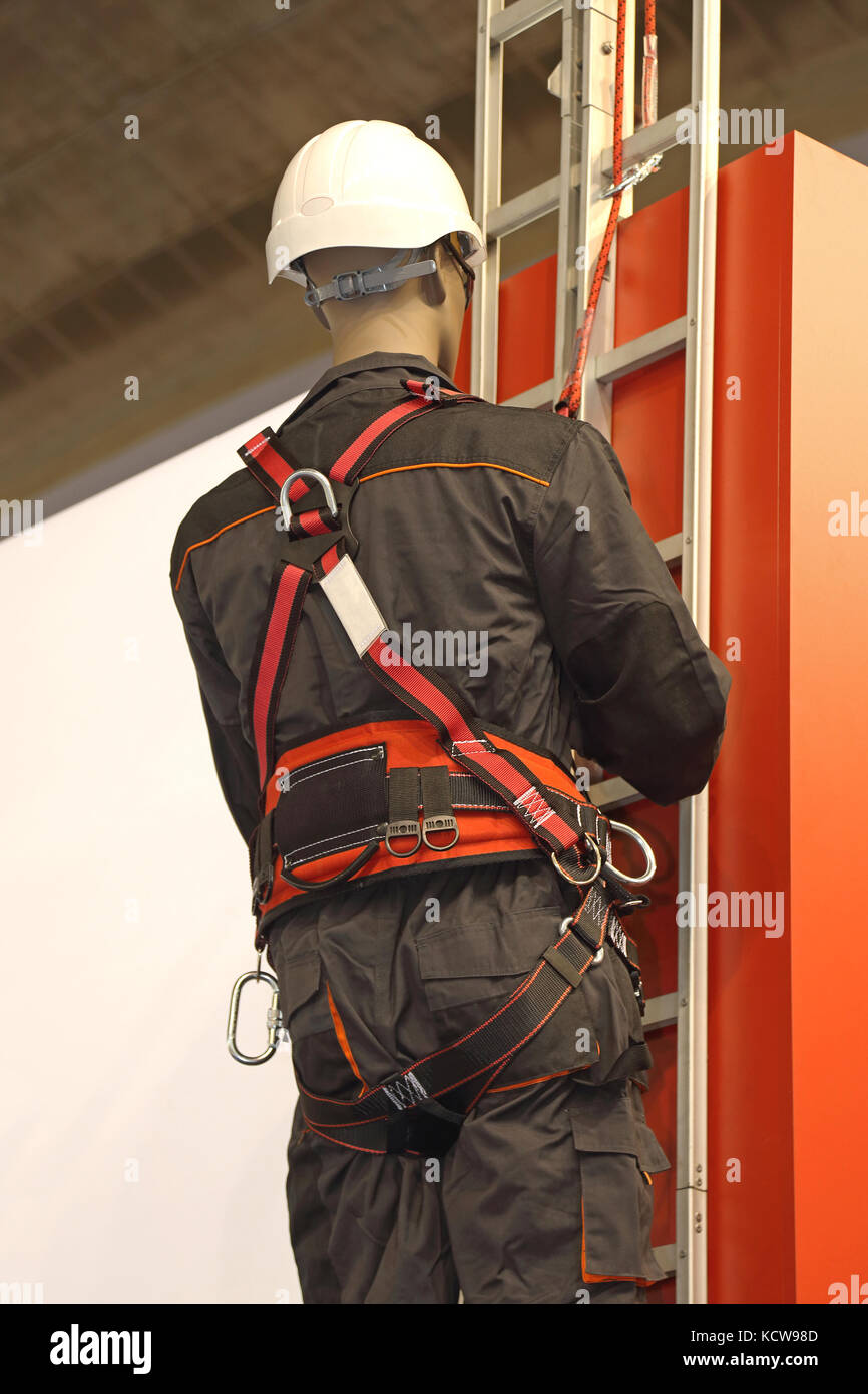 Trabajador en una escalera utiliza un arnés de seguridad para evitar caídas  del edificio Fotografía de stock - Alamy