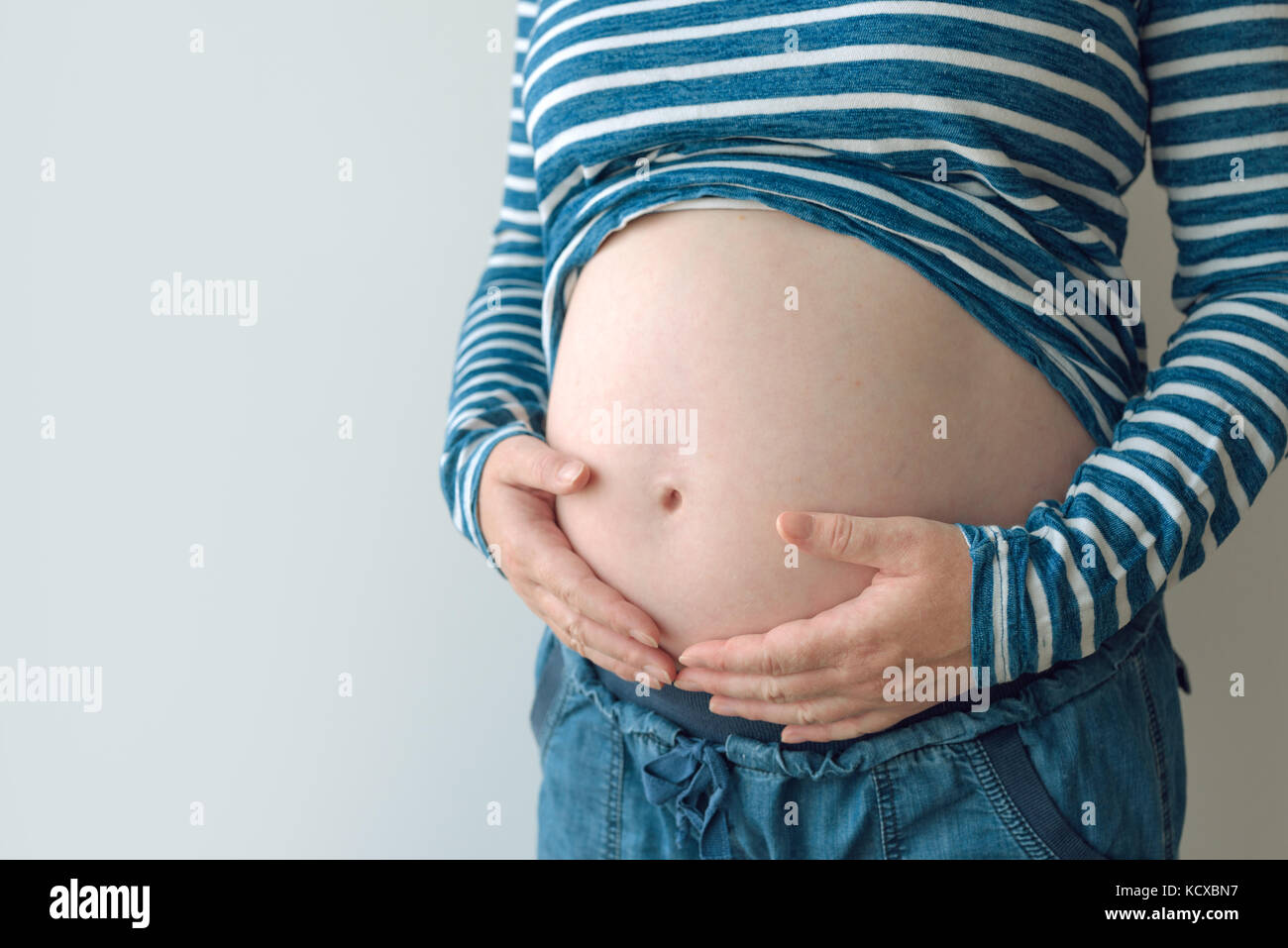 Mujer embarazada tocando y frota su vientre, madre de acariciar y estimular el abdomen, Cáucaso adulto femenino en el quinto mes o 21º semana de Foto de stock