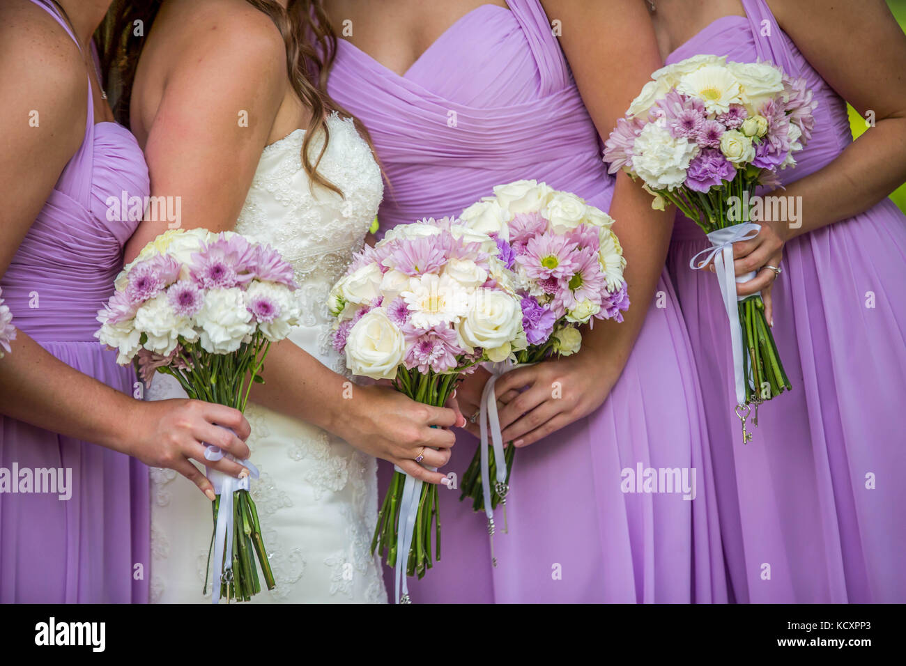 Una esposa y tres vestidos de de honor de púrpura o lila sosteniendo un hermoso arreglo floral de lavanda y ramos de flores blancas Fotografía de stock - Alamy