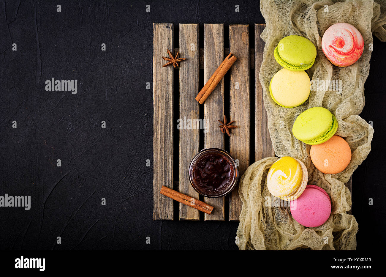 Coloridos macarons y un tarro de miel sobre un fondo de madera plana vista superior de la lay. Foto de stock