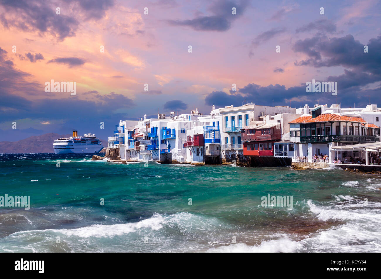 La pequeña Venecia, la isla de Mykonos, Grecia. los coloridos edificios y balcones cerca del mar y de un barco de crucero blanco grande. Foto de stock