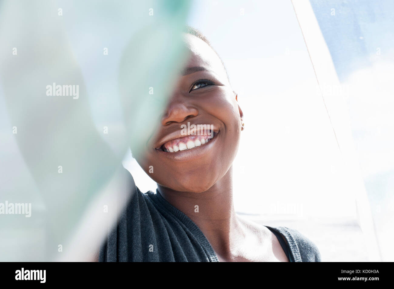Retrato de mujer joven en la playa, sonriendo, sosteniendo pura bufanda Foto de stock