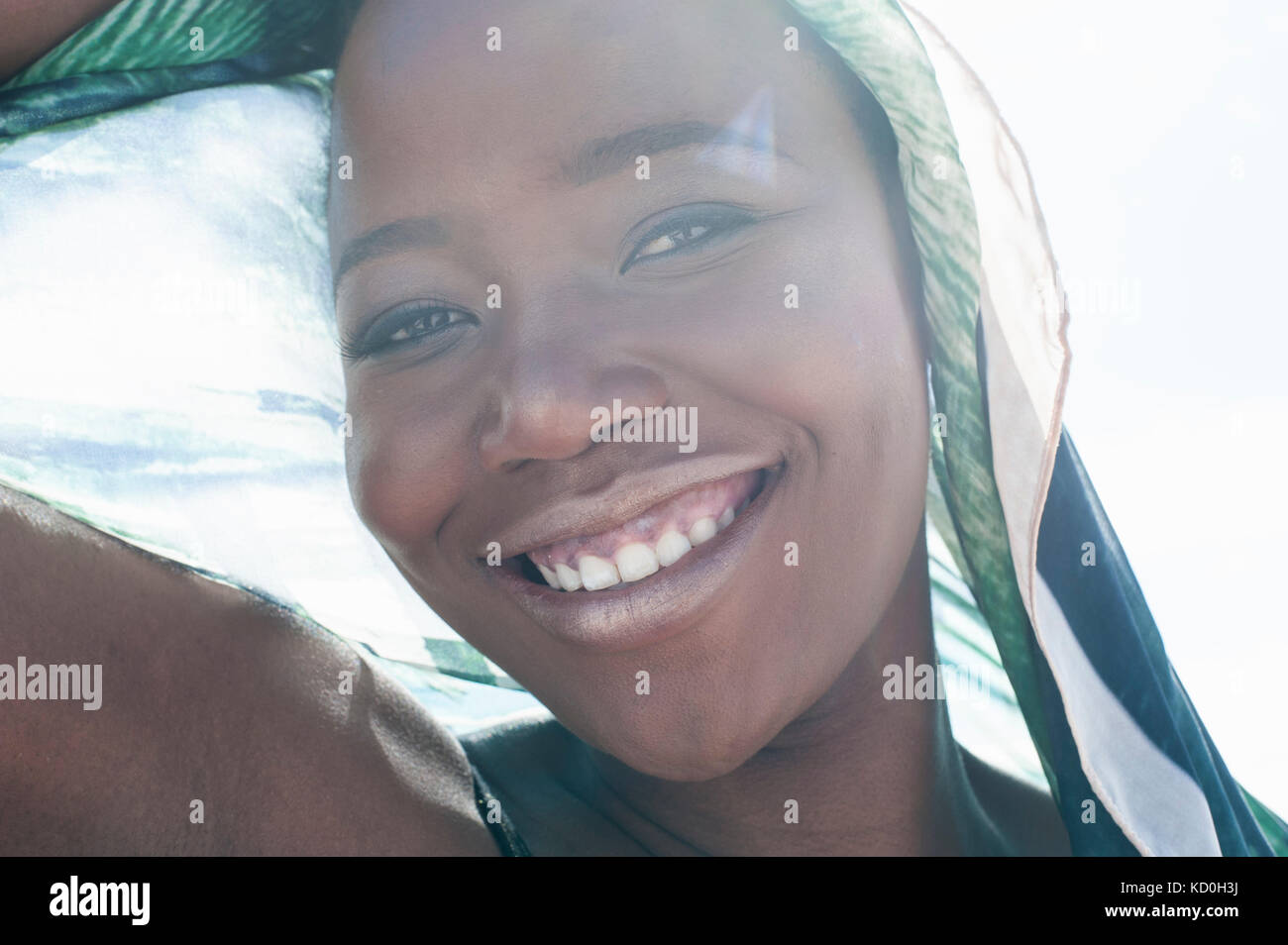Retrato de mujer joven en la playa, una sonrisa enorme bufanda envuelto alrededor de ella, close-up Foto de stock
